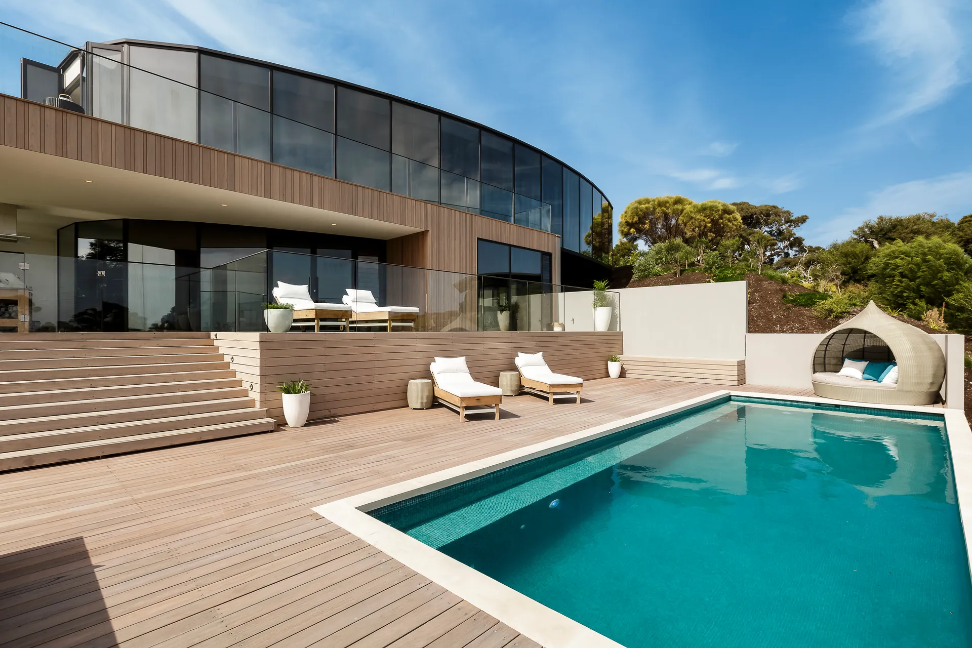 Maison contemporaine avec terrasse en bois et piscine en journée, illustration d’un séjour de vacances